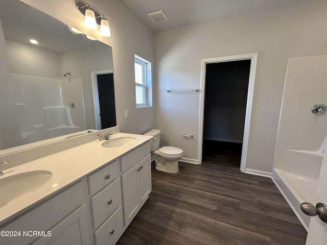 bathroom with hardwood / wood-style flooring, toilet, vanity, and walk in shower