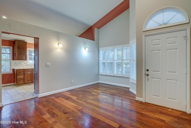 foyer with high vaulted ceiling and light hardwood / wood-style flooring