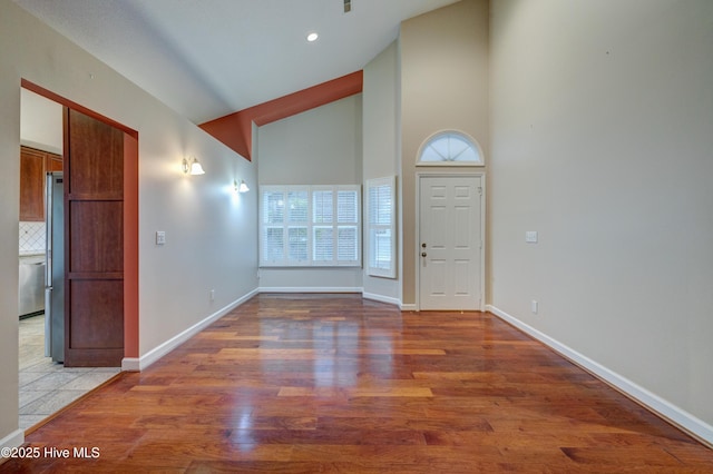 entrance foyer with wood-type flooring and high vaulted ceiling