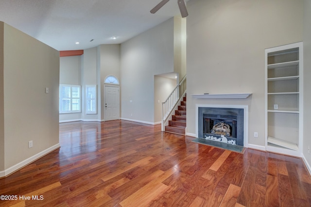 unfurnished living room with ceiling fan, high vaulted ceiling, hardwood / wood-style floors, and built in features