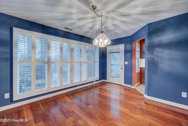 unfurnished room featuring an inviting chandelier and hardwood / wood-style floors