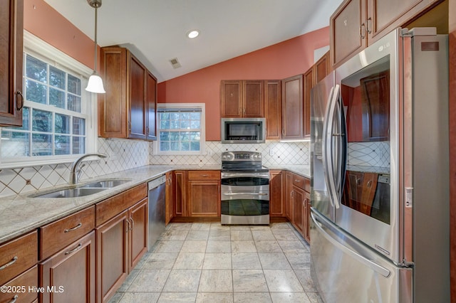 kitchen featuring lofted ceiling, sink, appliances with stainless steel finishes, hanging light fixtures, and light stone counters