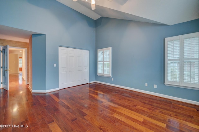 unfurnished bedroom featuring hardwood / wood-style flooring, ceiling fan, high vaulted ceiling, and a closet