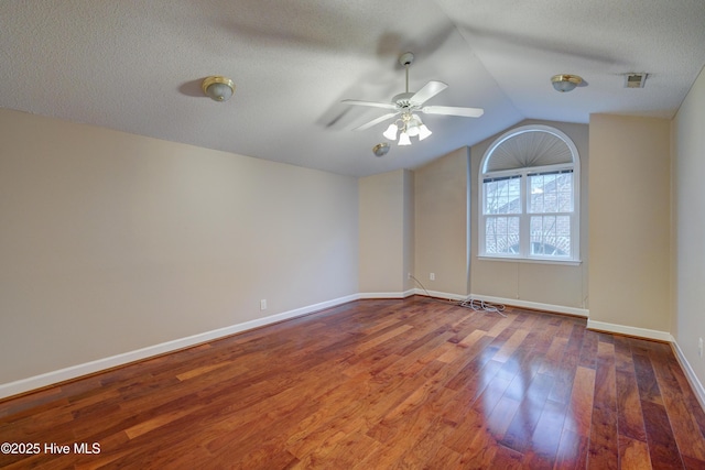 empty room with hardwood / wood-style flooring, ceiling fan, lofted ceiling, and a textured ceiling