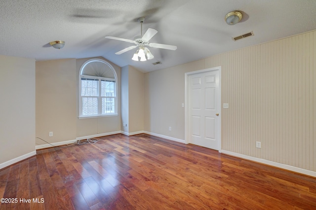 empty room featuring lofted ceiling, ceiling fan, hardwood / wood-style flooring, and a textured ceiling