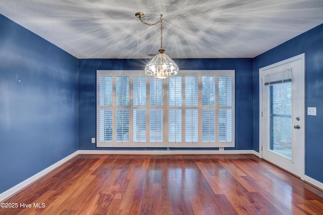 unfurnished dining area featuring hardwood / wood-style floors and a notable chandelier