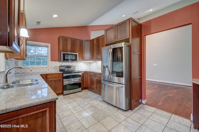 kitchen with lofted ceiling, sink, light tile patterned floors, appliances with stainless steel finishes, and light stone counters