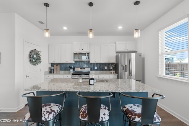 kitchen featuring appliances with stainless steel finishes, white cabinets, tasteful backsplash, and light stone counters