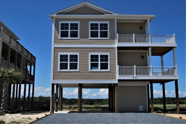 raised beach house featuring a balcony, driveway, and a carport