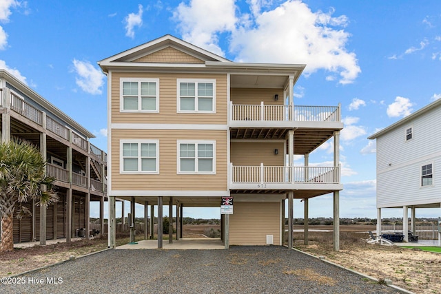 beach home featuring gravel driveway, a carport, and a balcony