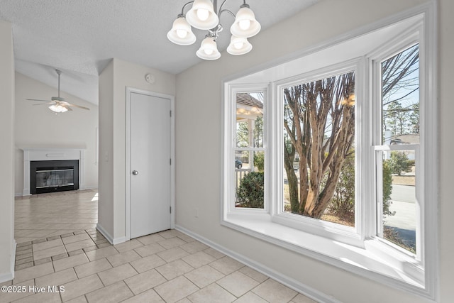 unfurnished dining area with light tile patterned floors, a textured ceiling, a wealth of natural light, and a glass covered fireplace