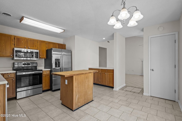 kitchen with visible vents, butcher block counters, a kitchen island, appliances with stainless steel finishes, and brown cabinets