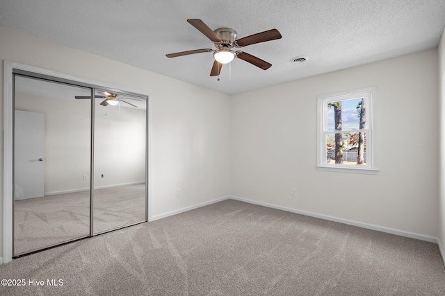 unfurnished bedroom with a textured ceiling, carpet flooring, visible vents, baseboards, and a closet