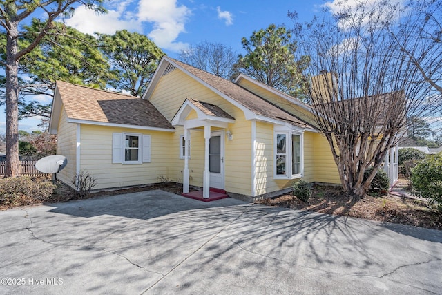 view of front of house with a shingled roof and fence