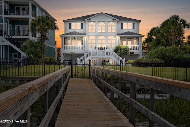 57 Craven St, Ocean Isle Beach, NC 28469 - back of property at dusk featuring stairs, a fenced front yard, and a porch