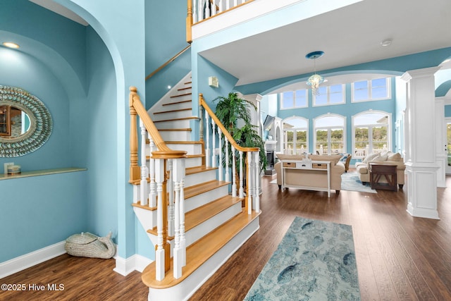 57 Craven St, Ocean Isle Beach, NC 28469 - stairs with arched walkways, wood finished floors, ornate columns, and a towering ceiling
