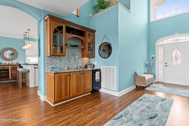 57 Craven St, Ocean Isle Beach, NC 28469 - indoor bar with dark wood-type flooring, backsplash, a high ceiling, arched walkways, and pendant lighting