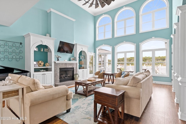57 Craven St, Ocean Isle Beach, NC 28469 - living area featuring a high ceiling, ornamental molding, a premium fireplace, hardwood / wood-style flooring, and built in shelves