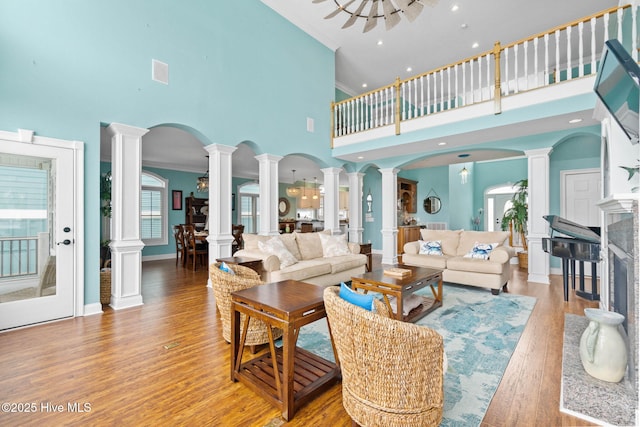 57 Craven St, Ocean Isle Beach, NC 28469 - living room with a high ceiling, decorative columns, light wood-style flooring, arched walkways, and crown molding