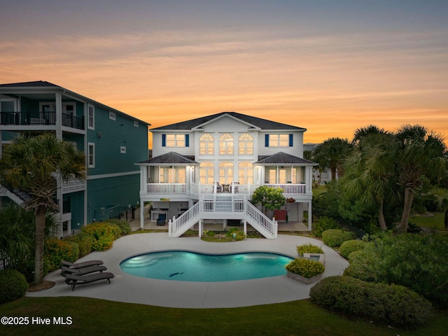 57 Craven St, Ocean Isle Beach, NC 28469 - back of property featuring stairway, a patio, an outdoor pool, and a shingled roof