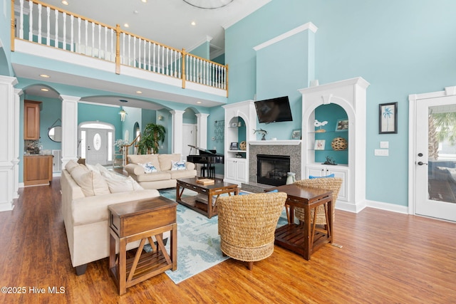 57 Craven St, Ocean Isle Beach, NC 28469 - living area with decorative columns, a towering ceiling, wood finished floors, a fireplace with raised hearth, and built in shelves