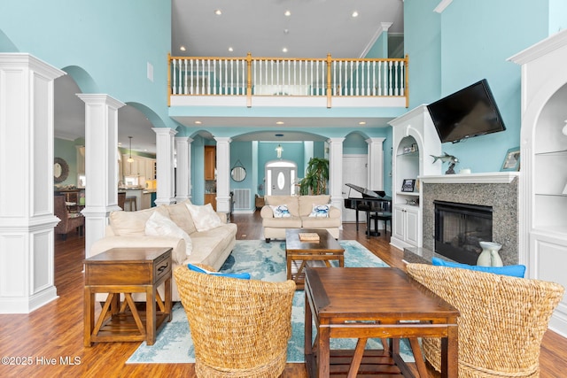 57 Craven St, Ocean Isle Beach, NC 28469 - living area with ornate columns, wood finished floors, a high ceiling, a fireplace, and recessed lighting
