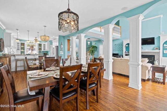 57 Craven St, Ocean Isle Beach, NC 28469 - dining room featuring wood finished floors, arched walkways, ornate columns, and a glass covered fireplace