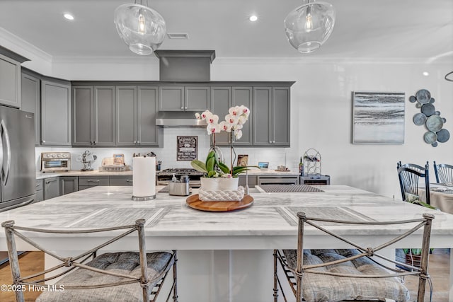 kitchen featuring gray cabinets, a center island with sink, and stainless steel fridge