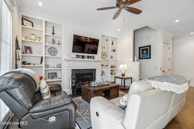 living room with crown molding, hardwood / wood-style floors, built in features, and ceiling fan