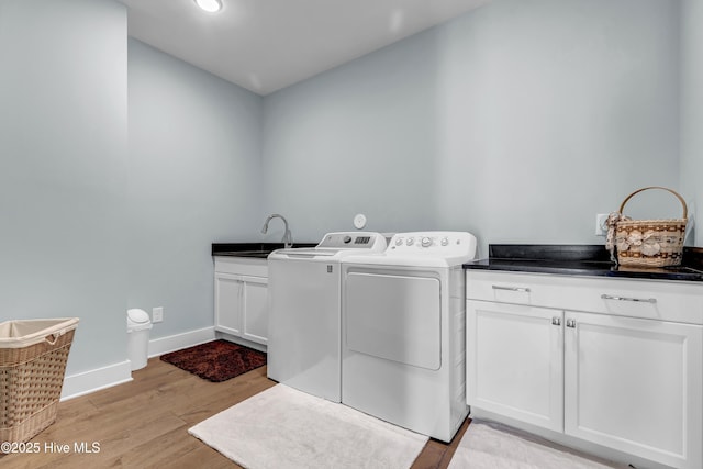 clothes washing area featuring cabinets, sink, light wood-type flooring, and washing machine and clothes dryer