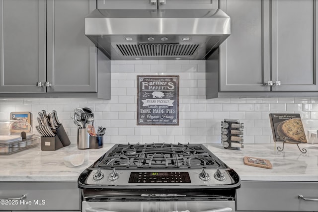 kitchen with gas stove, extractor fan, gray cabinetry, light stone countertops, and decorative backsplash