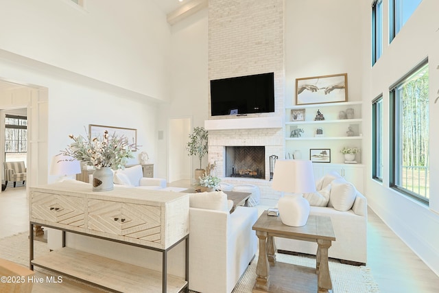 living area with built in features, a fireplace, a high ceiling, and wood finished floors