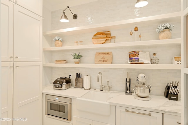 bar with tasteful backsplash, a sink, wall oven, and built in microwave