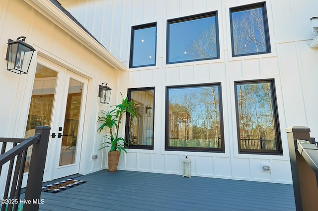 view of exterior entry featuring board and batten siding and a wooden deck