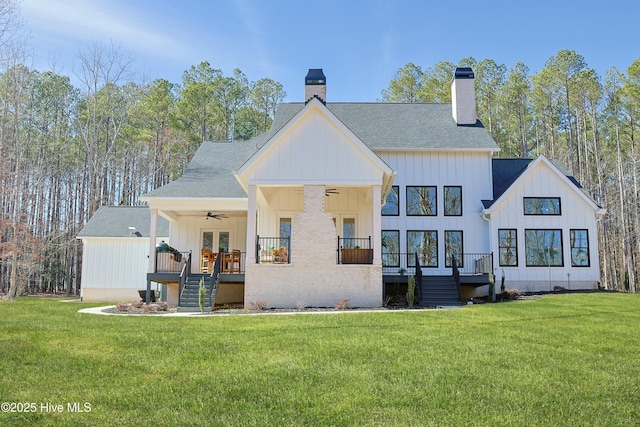 back of house with ceiling fan, a chimney, stairway, and a lawn