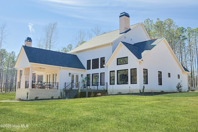 rear view of house with a yard, a chimney, a shingled roof, stairway, and a wooden deck