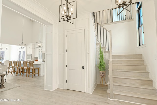 entryway featuring light wood finished floors, stairs, and a chandelier