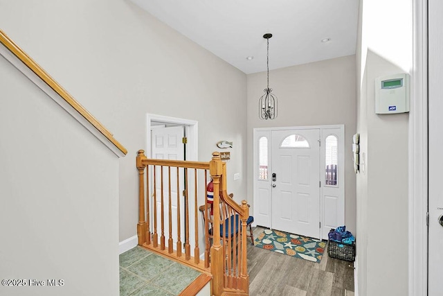 foyer entrance with hardwood / wood-style flooring, a chandelier, and a towering ceiling