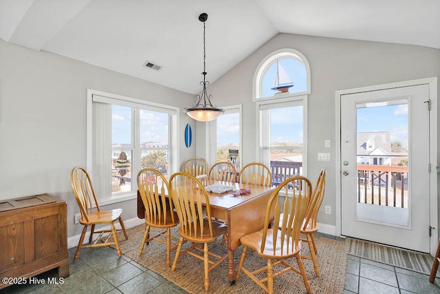 dining space with dark tile patterned floors and vaulted ceiling