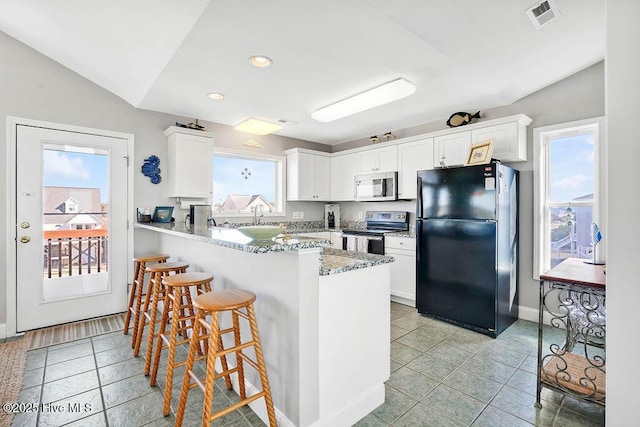 kitchen featuring a kitchen breakfast bar, stainless steel appliances, white cabinets, light tile patterned floors, and kitchen peninsula