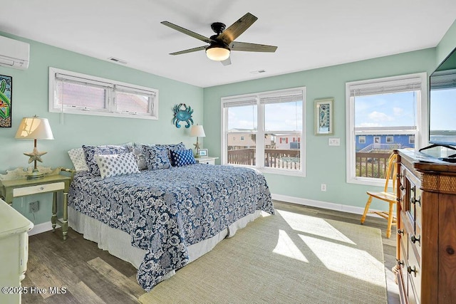 bedroom with multiple windows, hardwood / wood-style flooring, a wall mounted air conditioner, and ceiling fan