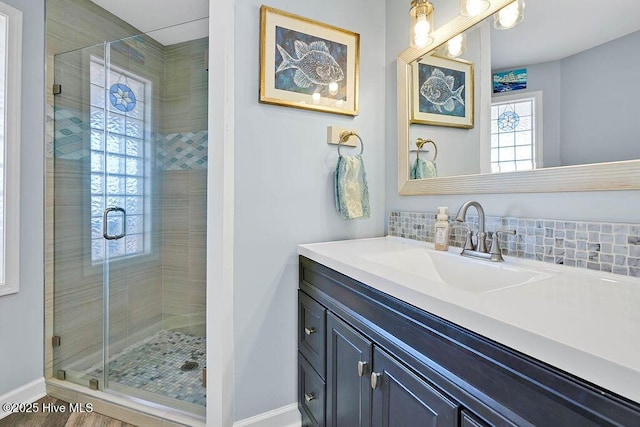 bathroom with vanity, backsplash, and walk in shower