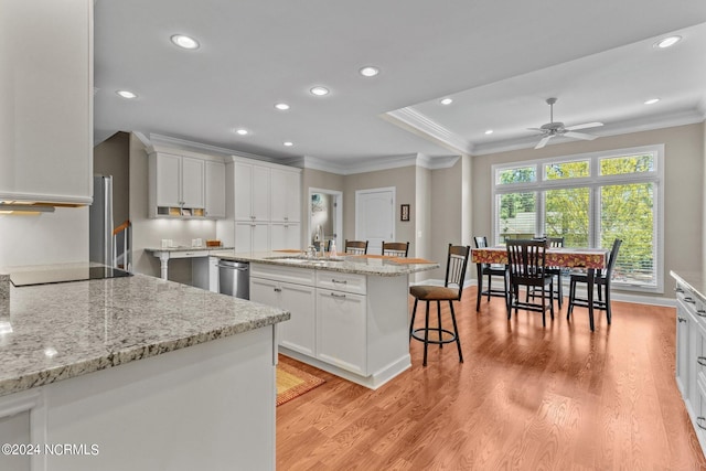 kitchen with sink, crown molding, white cabinetry, a kitchen island, and stainless steel dishwasher