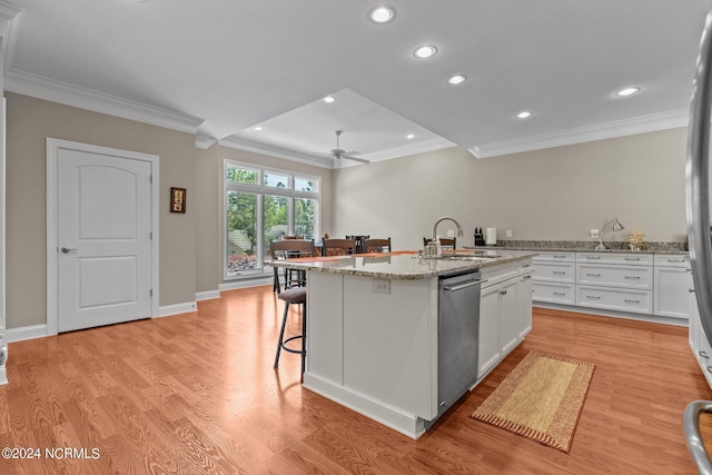 kitchen featuring sink, dishwasher, light stone counters, white cabinets, and a center island with sink