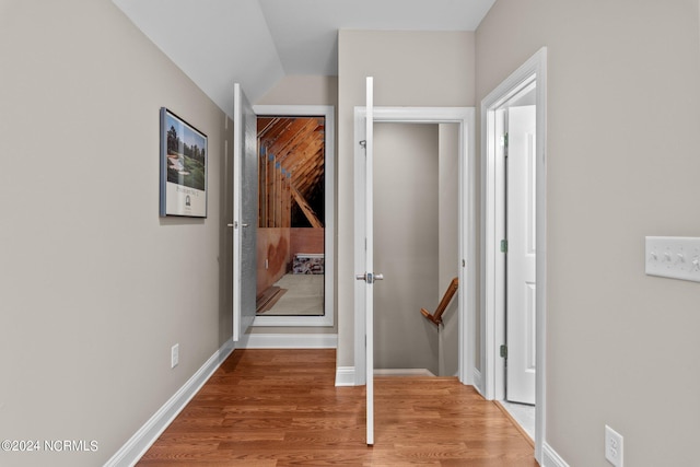 hall featuring lofted ceiling and hardwood / wood-style flooring