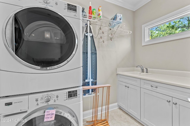 laundry area with light tile patterned flooring, stacked washer and dryer, sink, cabinets, and ornamental molding