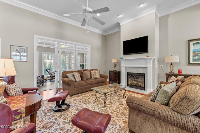 living room with a high end fireplace, ornamental molding, and ceiling fan