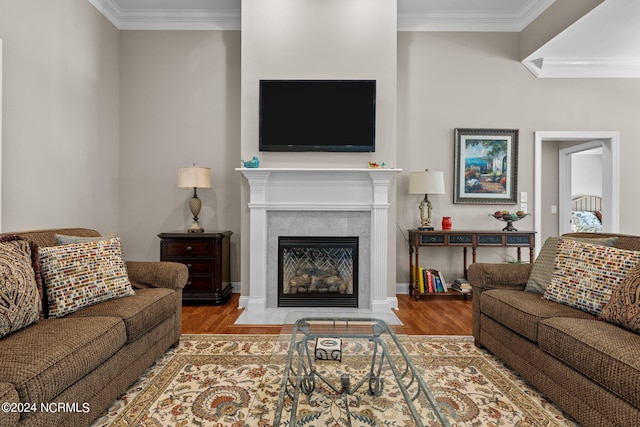 living room with a high end fireplace, wood-type flooring, and ornamental molding