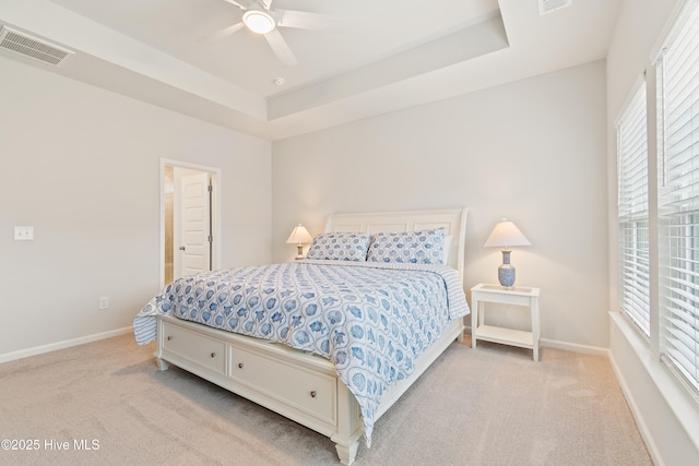 carpeted bedroom with ceiling fan and a tray ceiling