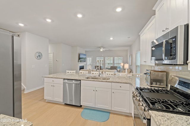 kitchen featuring sink, ceiling fan, appliances with stainless steel finishes, white cabinetry, and light hardwood / wood-style floors